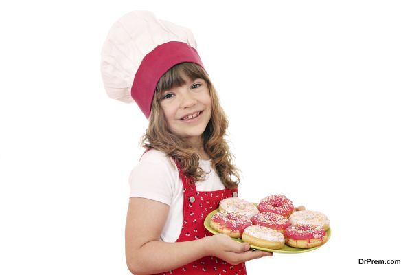 happy little girl cook with sweet donuts